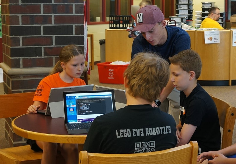 Alex teaching 3 students to program.